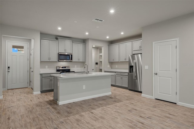 kitchen featuring gray cabinetry, a sink, visible vents, appliances with stainless steel finishes, and light wood finished floors