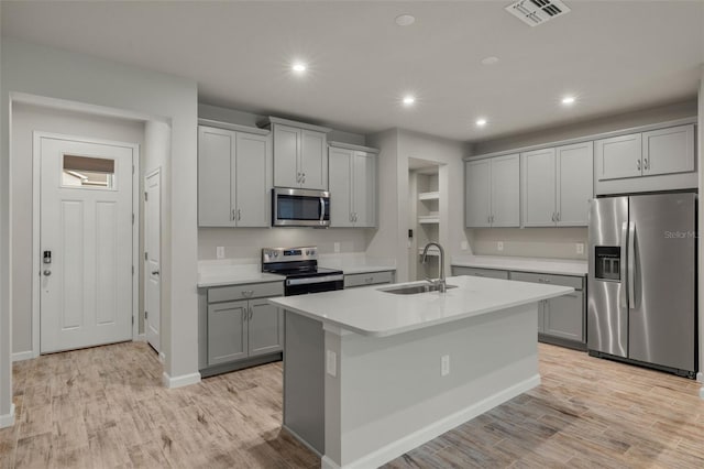 kitchen featuring stainless steel appliances, light wood finished floors, a sink, and gray cabinetry