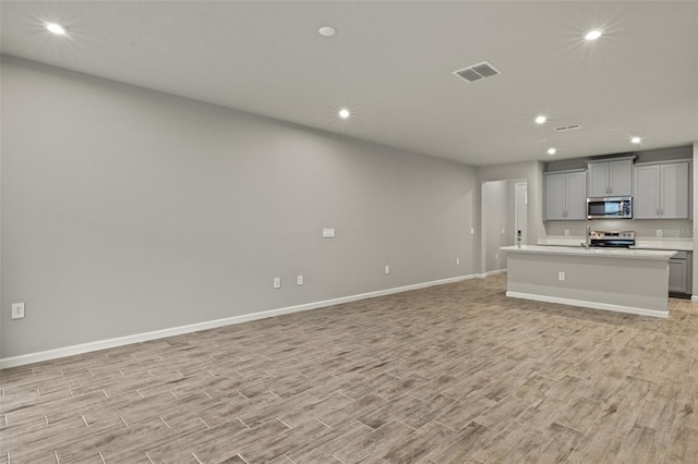 kitchen with open floor plan, light countertops, appliances with stainless steel finishes, and gray cabinetry