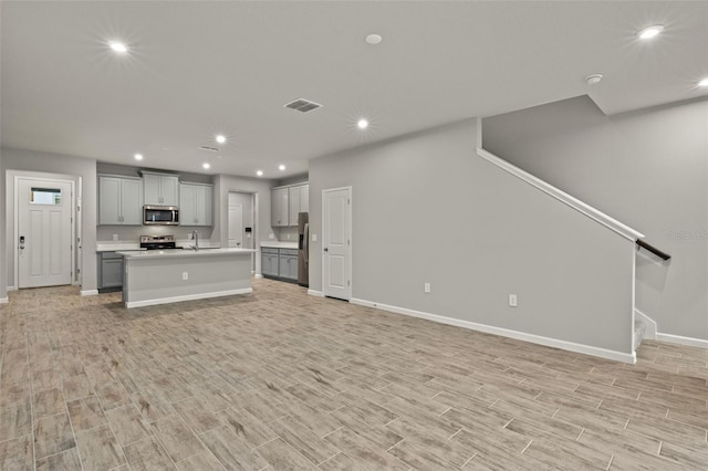 kitchen with gray cabinetry, stainless steel appliances, a sink, visible vents, and open floor plan