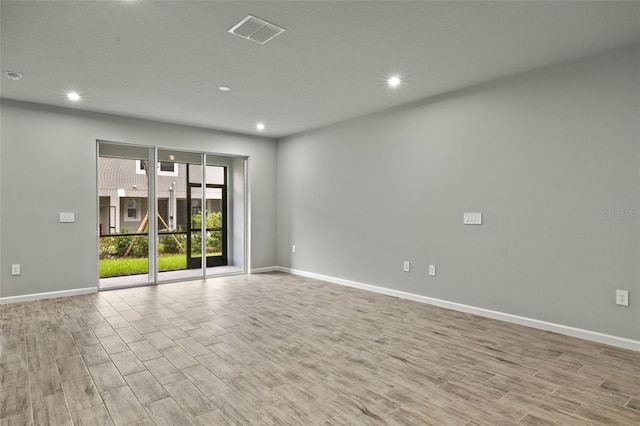 empty room featuring visible vents, baseboards, and wood finished floors