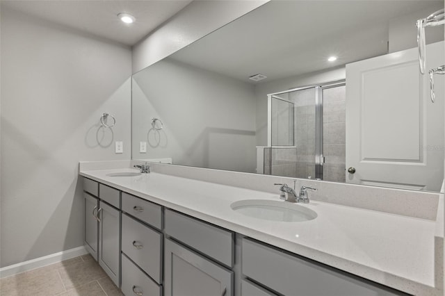 full bath with double vanity, baseboards, tile patterned flooring, a shower stall, and a sink