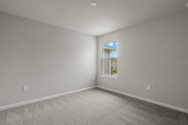 carpeted empty room with a textured ceiling and baseboards