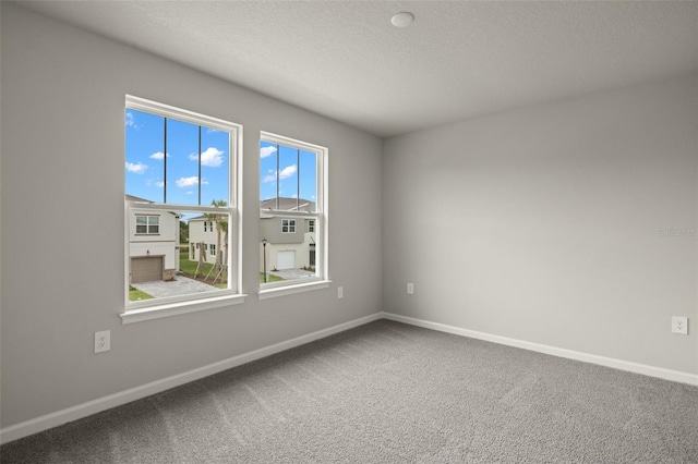 carpeted spare room with a textured ceiling and baseboards