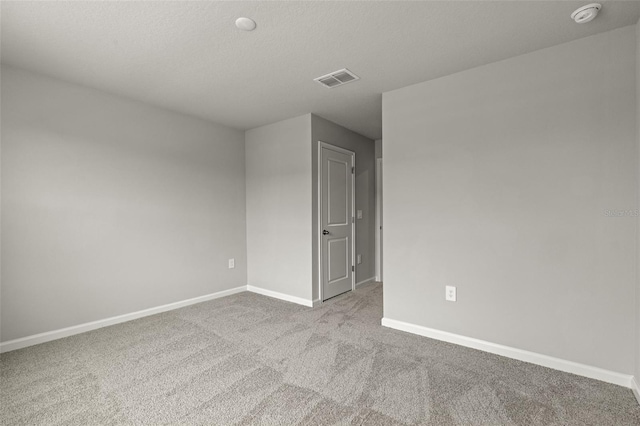 carpeted spare room featuring baseboards and a textured ceiling