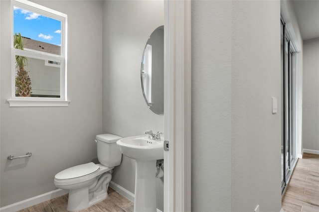 bathroom with wood finished floors, toilet, and baseboards