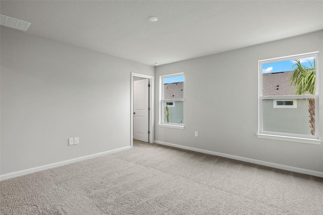 unfurnished room featuring visible vents, carpet, a wealth of natural light, and baseboards