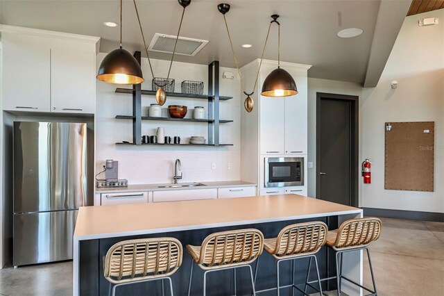 kitchen with built in microwave, a sink, visible vents, freestanding refrigerator, and decorative backsplash