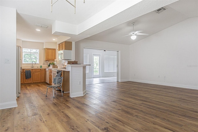 kitchen featuring ceiling fan, a breakfast bar area, kitchen peninsula, and wood-type flooring