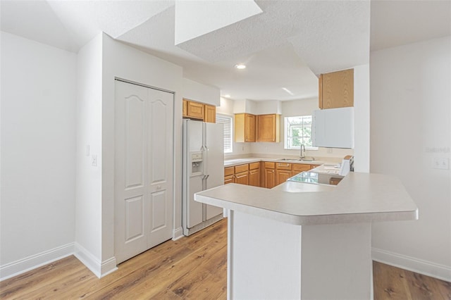 kitchen featuring light hardwood / wood-style floors, a textured ceiling, white appliances, and kitchen peninsula