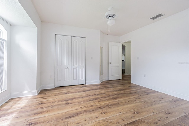 unfurnished bedroom with ceiling fan, light wood-type flooring, and a closet