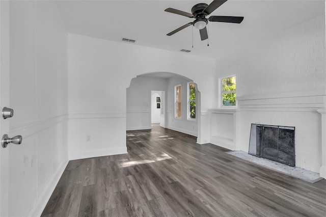 unfurnished living room with ceiling fan, dark hardwood / wood-style floors, and a brick fireplace