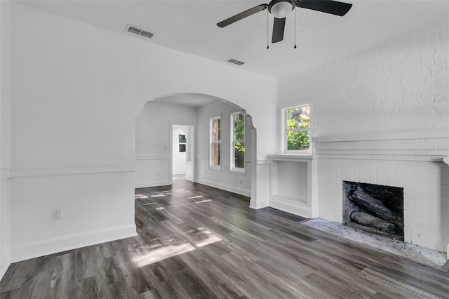 unfurnished living room with ceiling fan, dark hardwood / wood-style flooring, and a brick fireplace