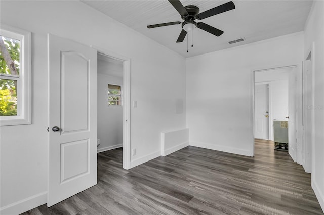 spare room featuring ceiling fan, dark wood-type flooring, and plenty of natural light