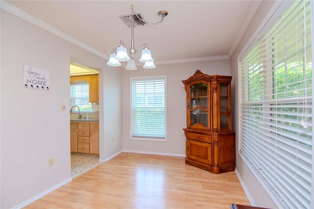 dining space with crown molding, light tile patterned floors, sink, and an inviting chandelier