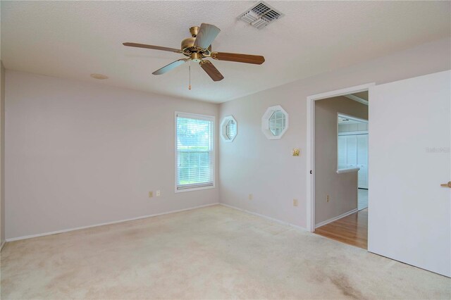 unfurnished room with ceiling fan and carpet