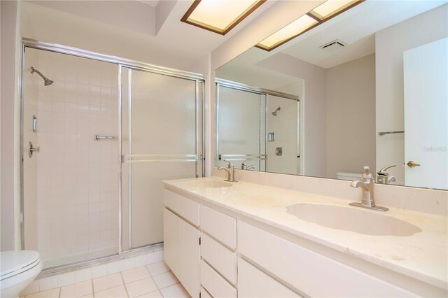 bathroom featuring dual bowl vanity, a shower with door, tile patterned flooring, and toilet