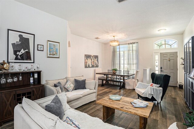 living room with dark wood-type flooring and an inviting chandelier