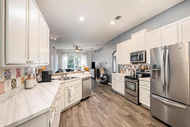 kitchen with wood-type flooring, sink, ceiling fan, appliances with stainless steel finishes, and white cabinets