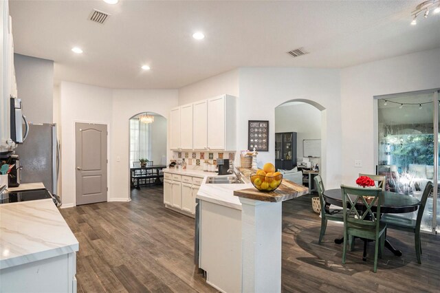 kitchen with white cabinets, appliances with stainless steel finishes, dark hardwood / wood-style flooring, sink, and kitchen peninsula