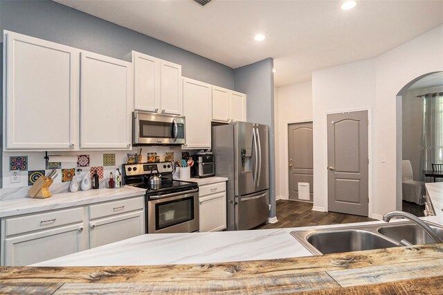 kitchen featuring dark wood-type flooring, sink, appliances with stainless steel finishes, and white cabinetry