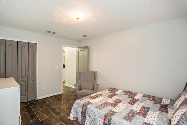 bedroom featuring dark hardwood / wood-style floors, a textured ceiling, and a closet