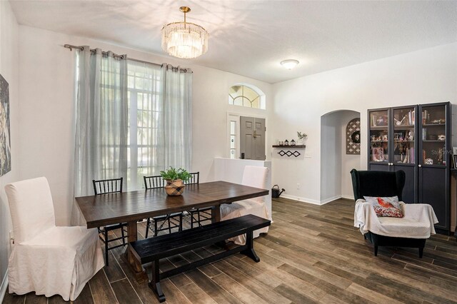 dining room with dark wood-type flooring, a wealth of natural light, and a notable chandelier