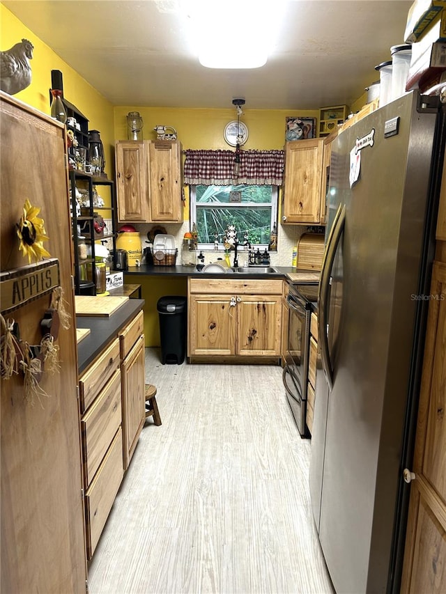 kitchen featuring electric range, stainless steel fridge, light hardwood / wood-style floors, and sink