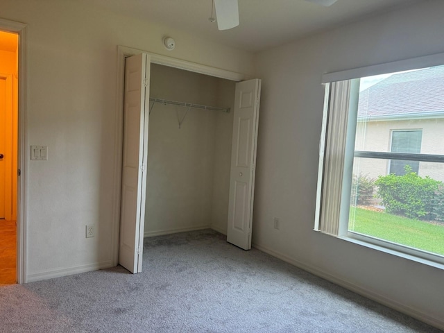 unfurnished bedroom featuring ceiling fan, a closet, and light colored carpet