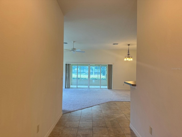 corridor with light colored carpet and a notable chandelier