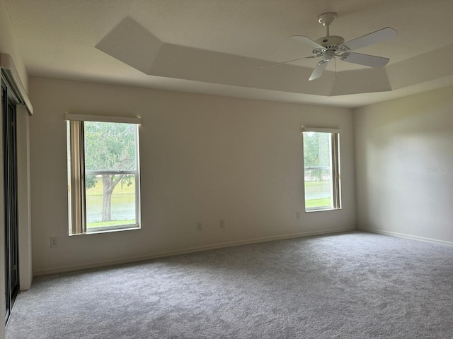 carpeted spare room featuring ceiling fan and a raised ceiling