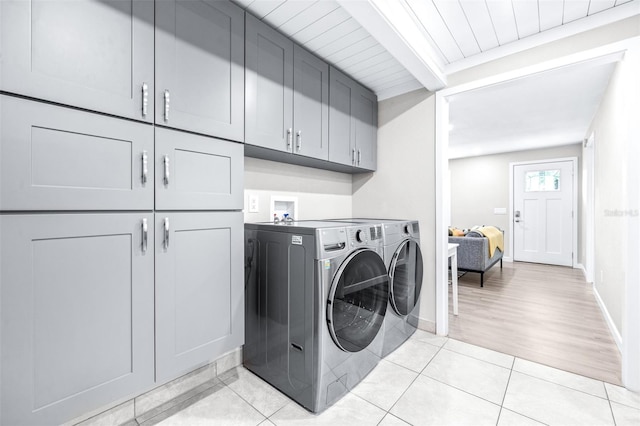 washroom featuring independent washer and dryer, cabinets, and light tile patterned flooring