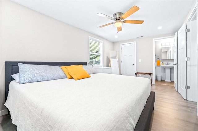 bedroom featuring ceiling fan, ensuite bathroom, and light hardwood / wood-style flooring