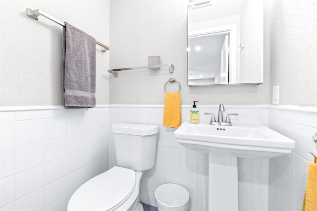 bathroom with tile walls, sink, and toilet