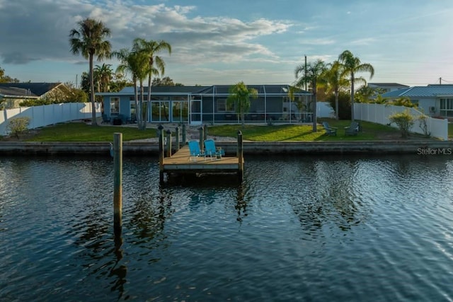 dock area featuring glass enclosure, a water view, and a yard