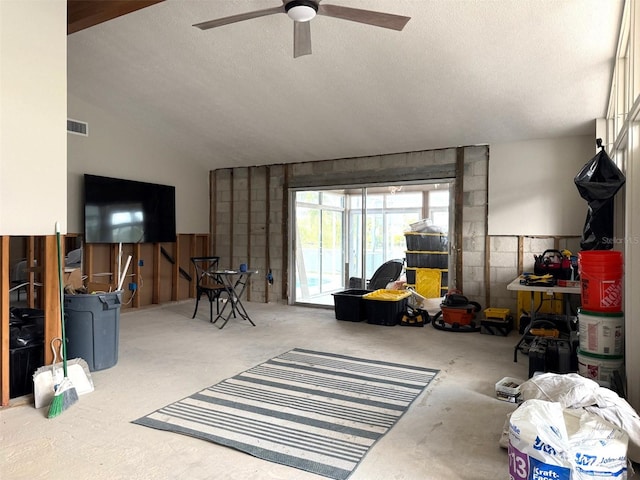 living room with a textured ceiling, ceiling fan, and lofted ceiling