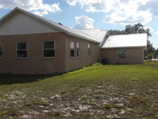 view of side of property featuring central air condition unit and a lawn