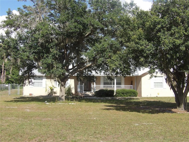 view of property hidden behind natural elements featuring a front yard and covered porch