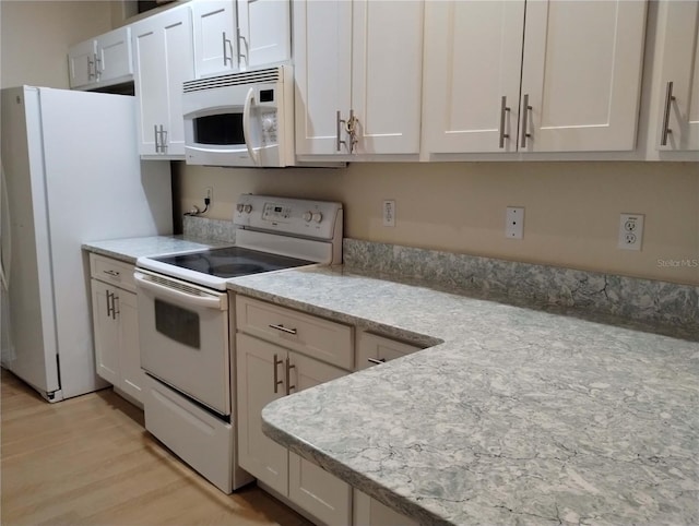 kitchen featuring white appliances, white cabinets, light stone countertops, and light hardwood / wood-style floors