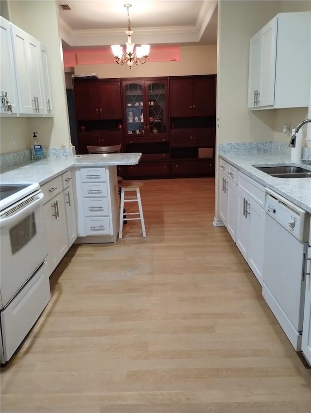 kitchen with white appliances, a chandelier, hanging light fixtures, white cabinetry, and sink