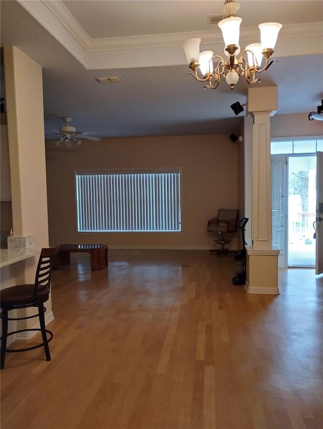 interior space with hardwood / wood-style floors, ornamental molding, a tray ceiling, decorative columns, and ceiling fan with notable chandelier