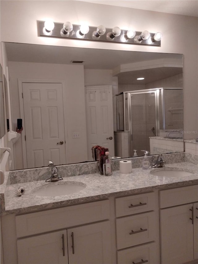 bathroom with a shower with door and vanity