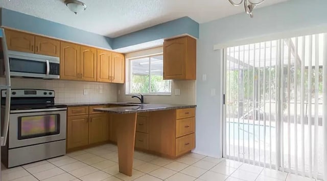 kitchen featuring dark stone counters, light tile patterned flooring, tasteful backsplash, sink, and appliances with stainless steel finishes