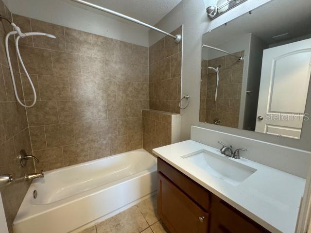 bathroom featuring tile patterned flooring, tiled shower / bath combo, and vanity