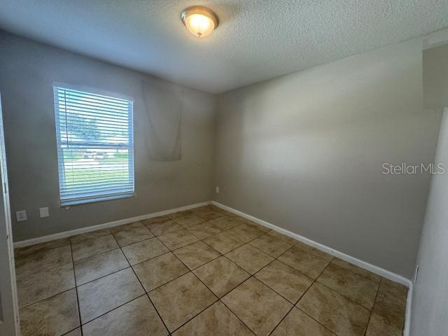 empty room with a textured ceiling and light tile patterned flooring