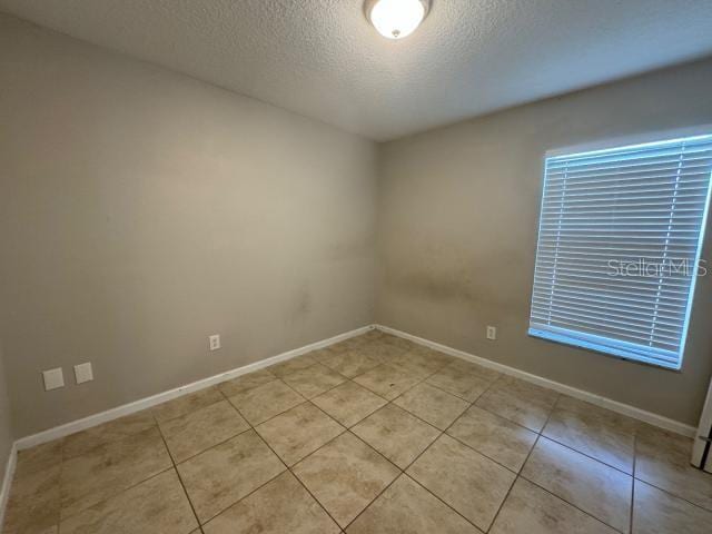 spare room with light tile patterned floors and a textured ceiling