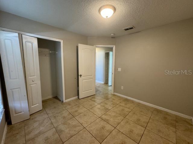 unfurnished bedroom featuring a closet, a textured ceiling, and light tile patterned flooring