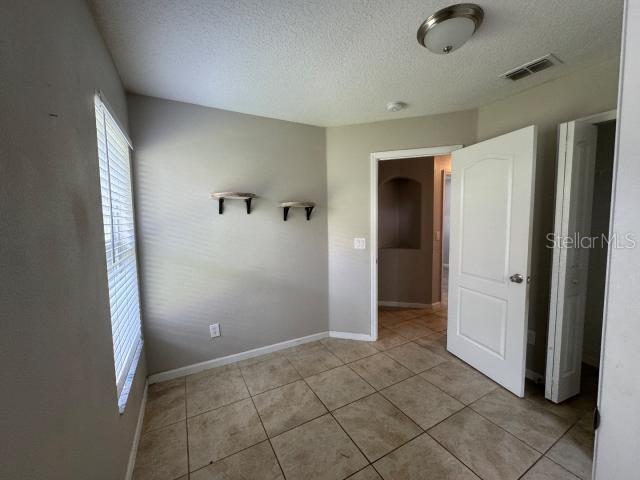 unfurnished bedroom with a textured ceiling and light tile patterned floors