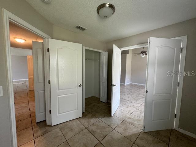 unfurnished bedroom featuring a closet, a textured ceiling, and light tile patterned flooring