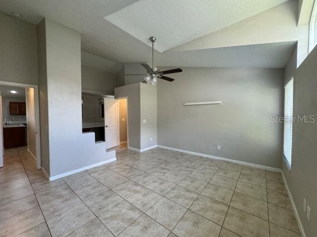 tiled empty room featuring ceiling fan, sink, a textured ceiling, and high vaulted ceiling